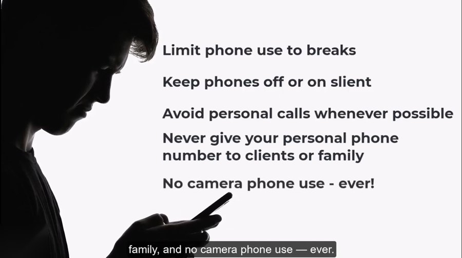 Video frame: a caregiver's silhouette looking at a phone, on-screen text lists five phone-use rules ending in no camera phone use, ever.
